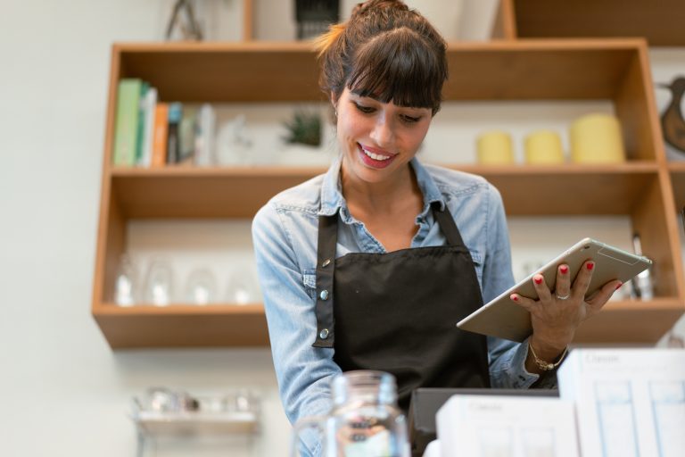 Smiling female coffee shop owner using digital tablet receiving order